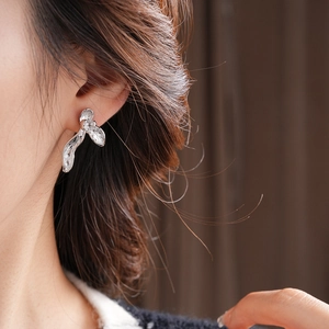 Macro side view of silver orchid petal earring worn by model with textured surface