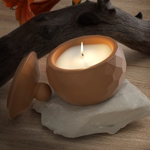 Artistic close-up of faceted geometric candle jar with lid and warm candle flame