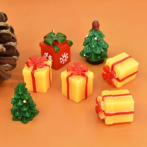 Miniature resin Christmas trees and gift box ornaments on a vibrant orange background
