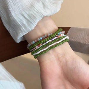 Detail of bohemian colorful seed bead bracelets set worn on a female wrist for layering