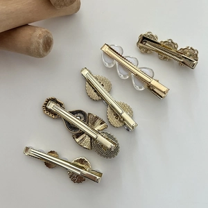 Elegant assortment of five metallic hair clips with pearls and rhinestones on white background
