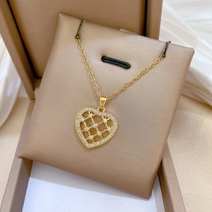 Vue macro d'un pendentif cœur doré serti de zircons dans un coffret cadeau à bijoux marron