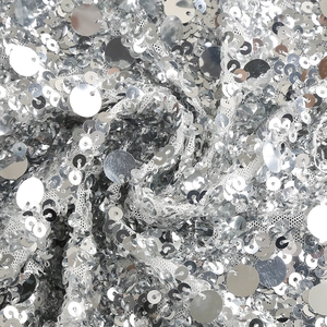 Macro shot of silver sequins on white mesh fabric for elegant evening evening gown