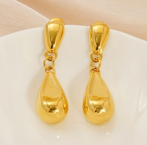 Macro view of polished 18K gold teardrop earrings with a smooth hollow texture