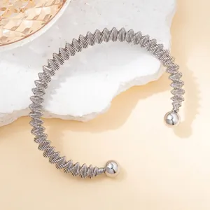Macro detail of silver stainless steel coil bracelet with polished metal bead ends