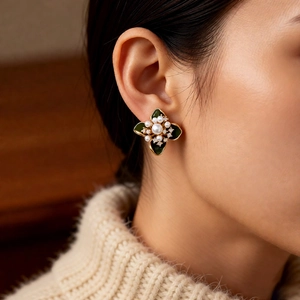 Détail de boucles d'oreilles fleurs plaquées or 18k avec émail vert et perles