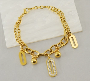 Détail d'un bracelet double chaîne en or 18K avec pendentif ovale en zircon et breloques
