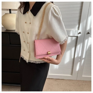 Detail of pink quilted crossbody bag with golden chain strap and metallic buckle