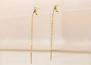 Detailed view of long gold crescent moon tassel threader earrings with fine hanging chains