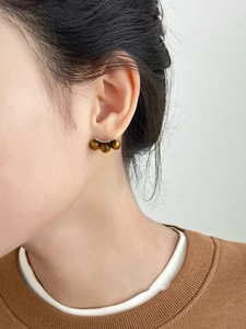 Close-up of model wearing tiger eye stone stud earrings with silver metal base