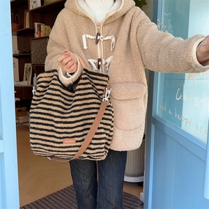 Macro shot of fluffy striped plush tote bag with logo label and durable canvas strap