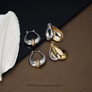 Macro shot of two-tone gold and silver horseshoe earrings and layered teardrop studs
