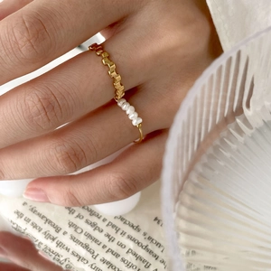 Minimalist gold chain ring with pearls shown on hand in a stylish lifestyle setting