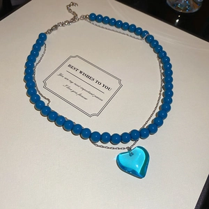 Detail of double-layer necklace with blue beads and heart pendant in gift box