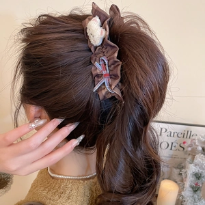 Détail d'une pince à cheveux à carreaux marron avec ours en peluche et ruban sur modèle