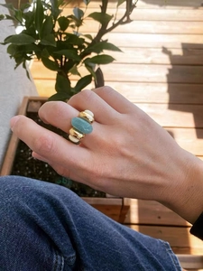 Macro view of a sculptural gold ring featuring a blue amazonite-style gemstone and white inlay