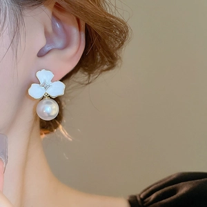 Close-up of elegant flower pearl earrings worn on ear showing fine craftsmanship