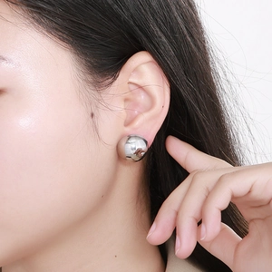 Close-up of polished silver hemispherical stud earring on model with mirror finish