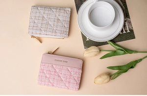 Detail of tweed and leather mini coin purses with golden zippers on elegant table