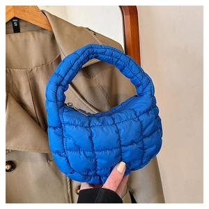 Close-up of bright blue quilted puffer bag with ruffled cloud texture and top zipper