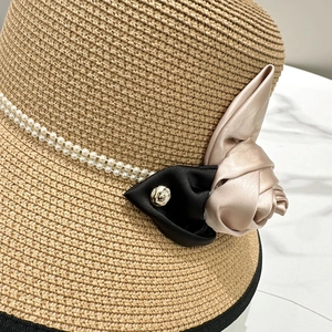 Détail de chapeau de soleil en paille avec chaîne de perles et fleur en satin élégante