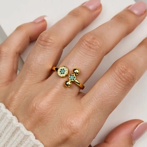 Detail of 18K gold X-shaped ring with blue and white zircons on a model's finger