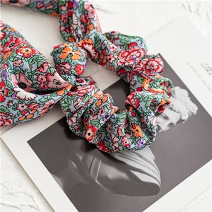 Detailed macro shot of floral print scrunchie with pastel blue fabric and elastic pleats