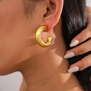 Golden chunky C-shape hoop earrings with vertical ridges on model for women
