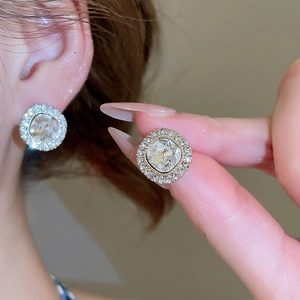 Close-up of sparkling round zircon stud earrings with a halo setting on a model