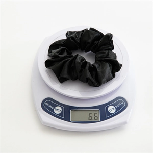 Detail showing a black satin scrunchie being weighed on a digital scale at 6.6 grams
