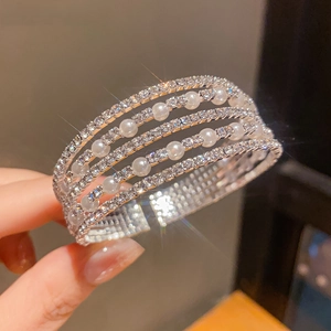 Macro detail of layered silver bracelet with imitation pearls and sparkling rhinestones