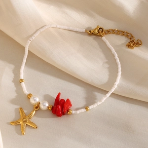 Detailed macro view of starfish charms and red coral beads on 18K gold bead bracelet