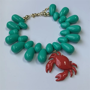 Detail of teal teardrop beads necklace with a vibrant red crab pendant and gold clasp