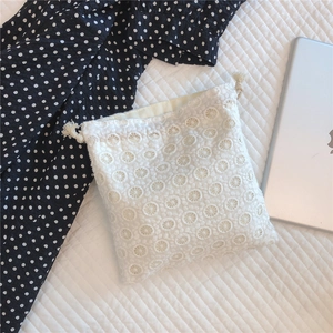 Detail shot of a white lace drawstring pouch with floral embroidery on soft fabric