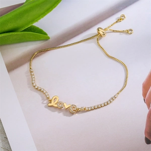 Detalle de pulsera dorada ajustable con letras LOVE y circonitas cúbicas brillantes