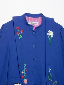 Macro detail of intricate floral embroidery on premium blue crepe texture jacket