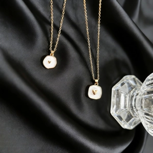 Golden chain necklaces with heart-patterned enamel charms on black silk fabric