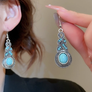 Detail of vintage bohemian hollow leaf earrings with turquoise stones and blue rhinestones