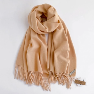 Dettaglio della morbida trama della sciarpa pashmina beige con eleganti nappe a frangia