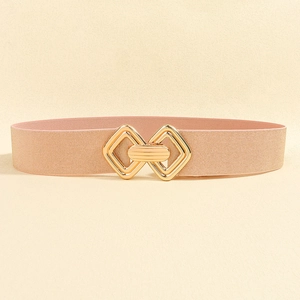Détail d'une ceinture élastique rose clair avec boucle géométrique en métal doré et texture