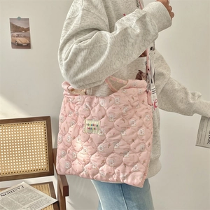 Detail of pink quilted tote bag featuring rabbit patterns and woven brand label