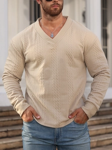 Detailed view of beige V-neck knit sweater featuring textured jacquard pattern fabric