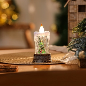 Detail view of a bronze Christmas candle snow globe lamp with an illuminated festive tree