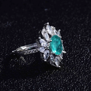 Detail of flower-shaped ring with green oval center stone and white zircons
