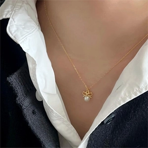 Elegant gold bow necklace with white pearl pendant worn on neck for a stylish look