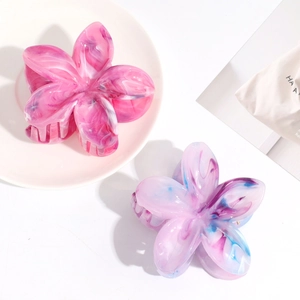 Close-up of pink marble and purple gradient flower hair claws on a ceramic plate