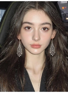 Close-up of model wearing silver hollow flower drop earrings with a vintage bohemian style
