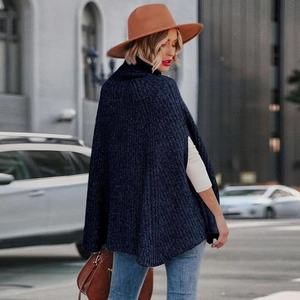 Dettaglio del poncho in maglia blu scuro con collo alto e trama spessa in lana pregiata