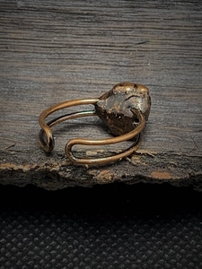 Detail of vintage adjustable ring with rough dark natural stone on rustic wood background