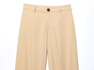 Detail of khaki trousers waist with belt loops and amber textured button closure